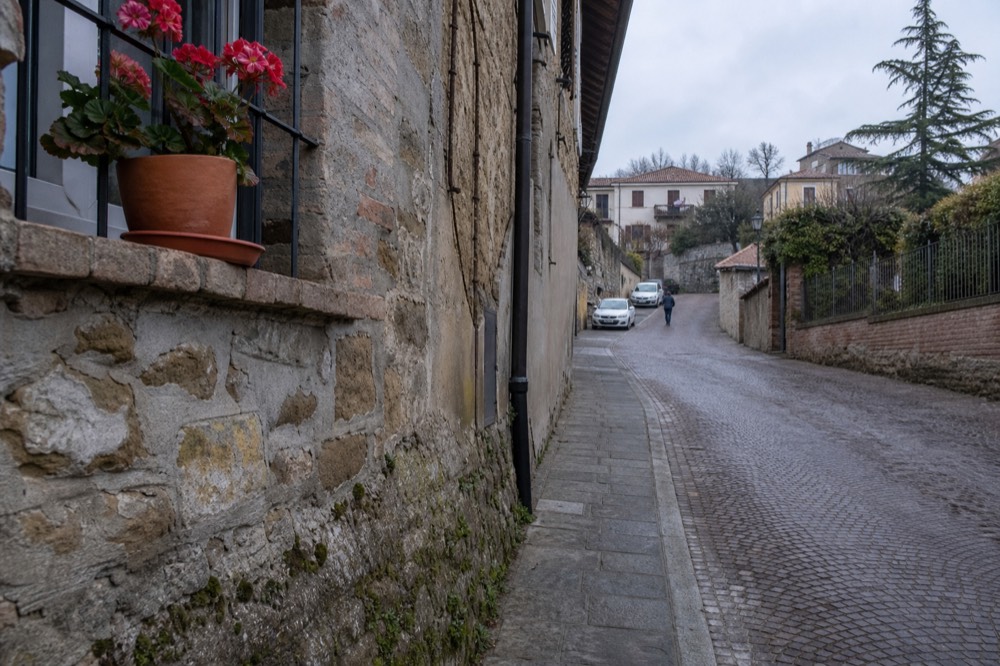 Pedal-assist e-bike parked beside a stone wall on a village street.