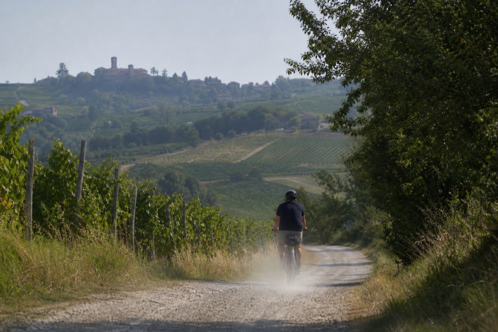 E-bike on a quiet Monferrato back road with vineyards on both sides.