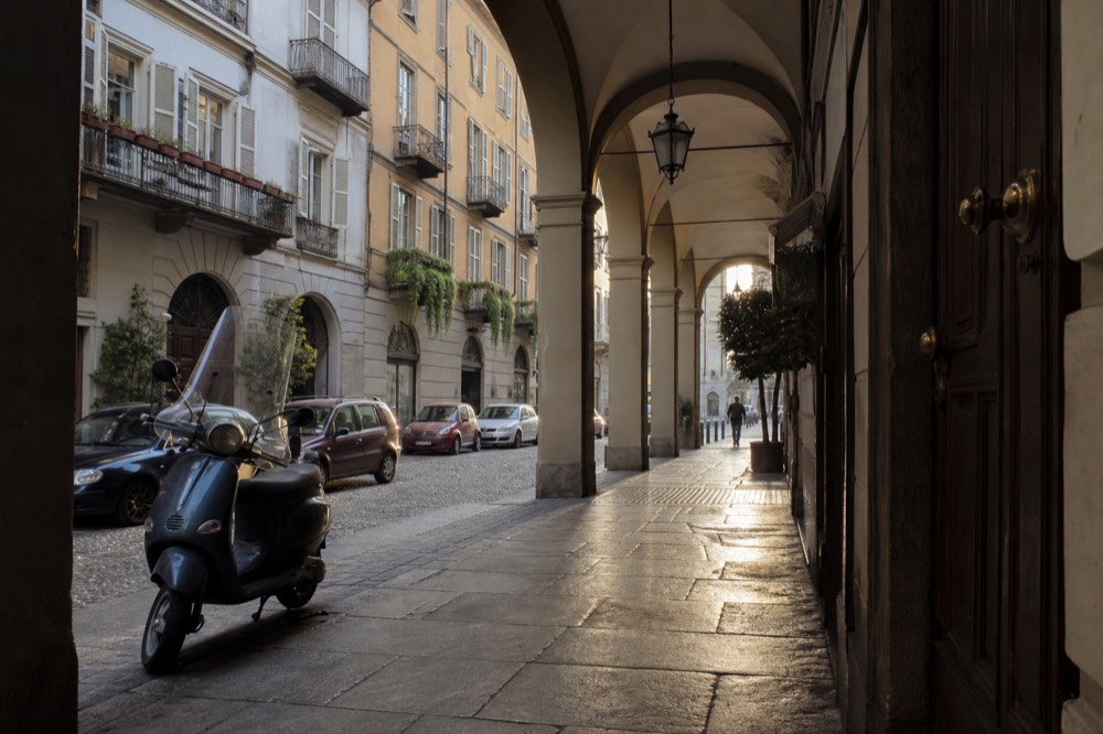 Turin-style arcaded street with historic facades in warm afternoon light.