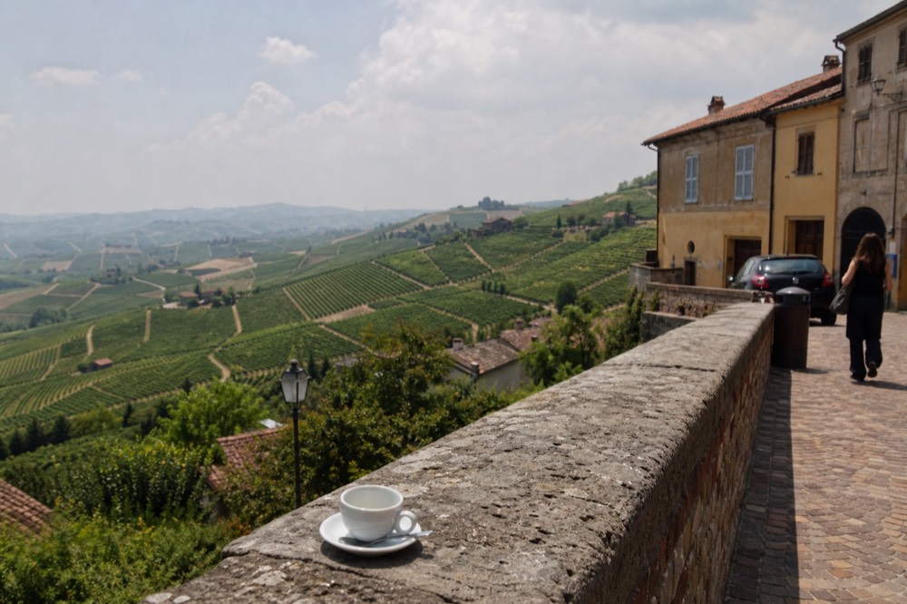 The terrace view over the Barolo vineyard amphitheatre from a hilltop village square.