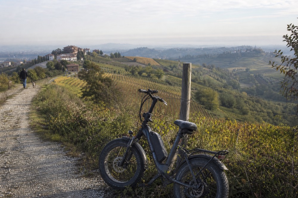 E-bike on a Monferrato ridge with vineyards and distant hills.