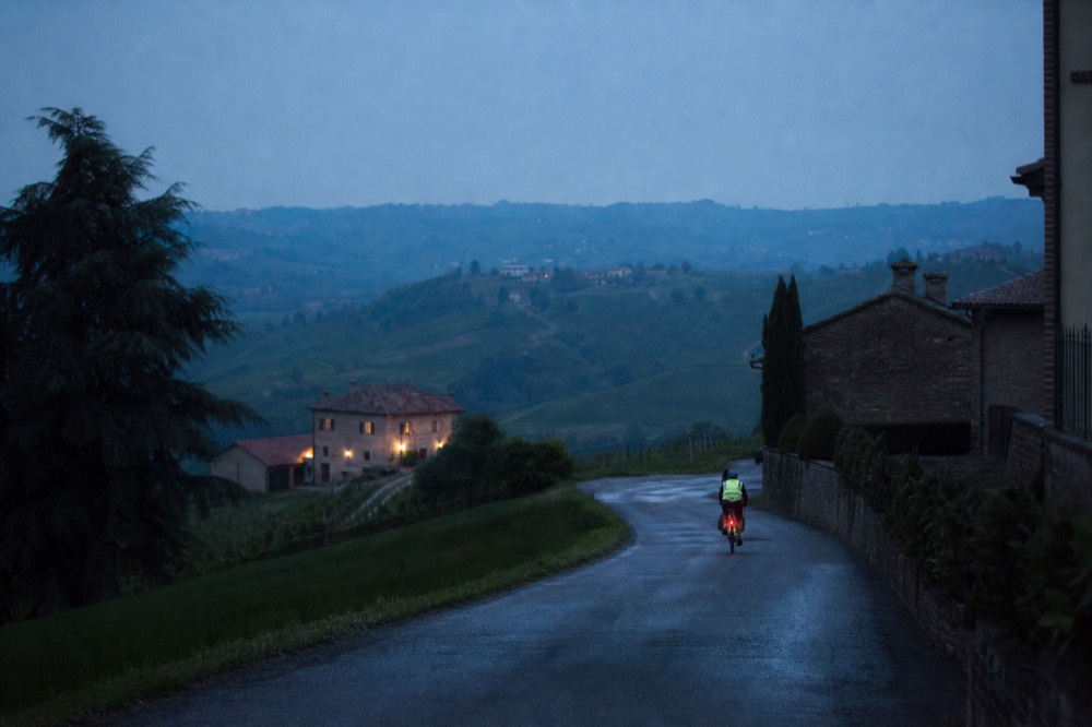 Cyclist silhouette on a country road at dusk with reflective vest visible.