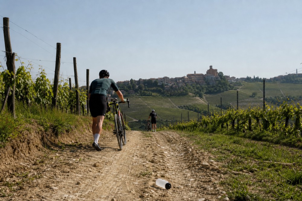 E-bike riders on a dirt road between Barolo vineyard rows.
