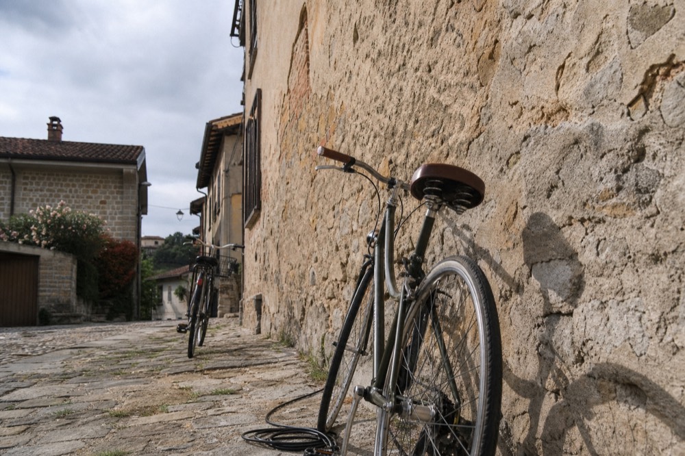 An e-bike parked outside a stone cellar building in a Langhe village.