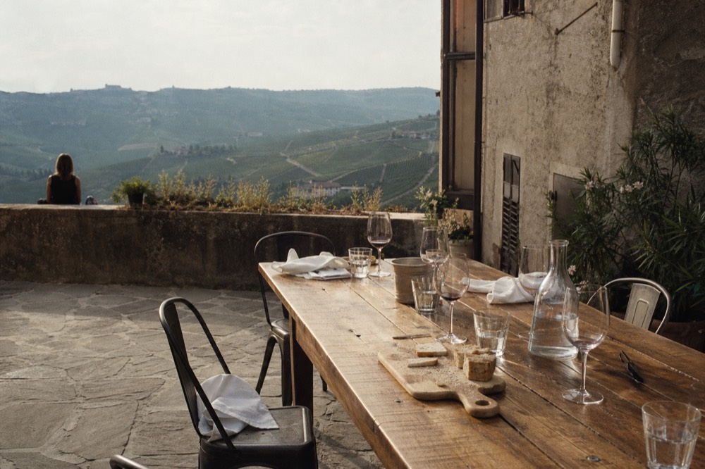 A long table set for lunch on a terrace above Barbaresco vineyards.