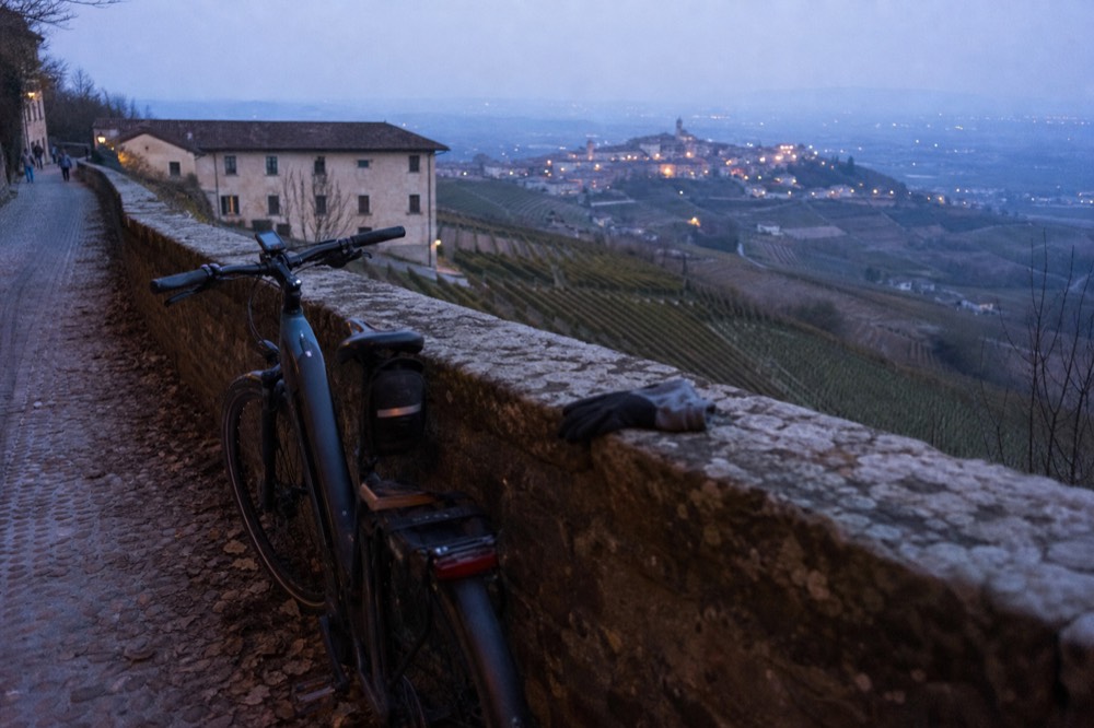 E-bike parked beside a vineyard with hills in background.