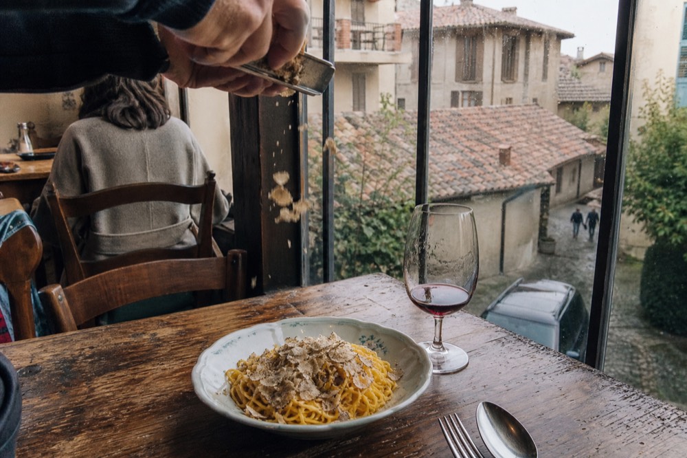 An autumn table with tajarin pasta being finished with shaved white truffle.